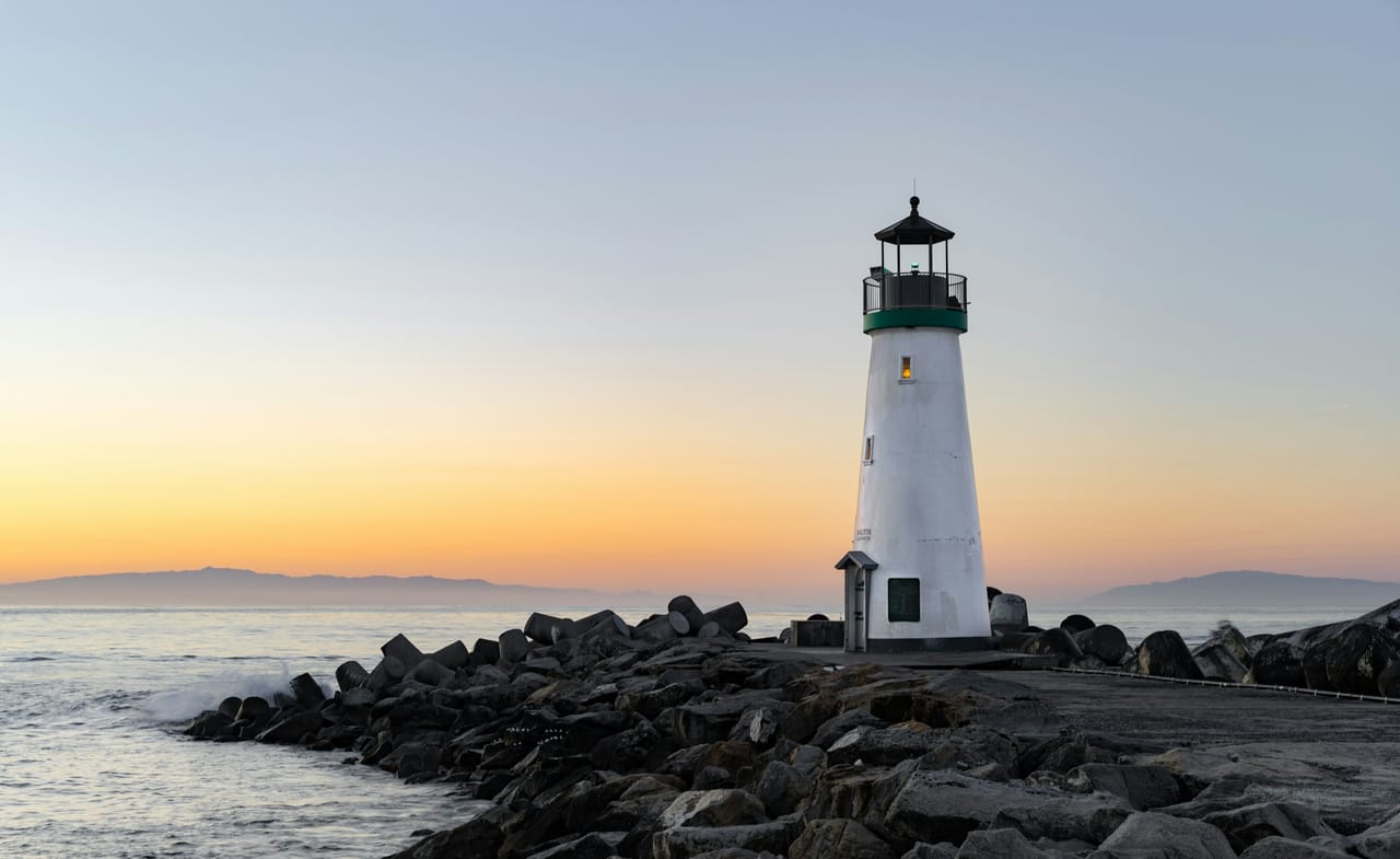 A lighthouse standing against a calm sky — structure and direction, the idea behind Met Maät